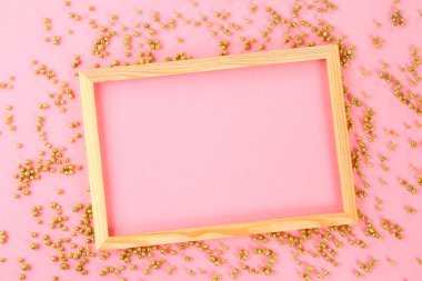 Parlak dekoratif yıldız ve topları çevrili pastel bir arka plan üzerinde ahşap bir boş çerçeve