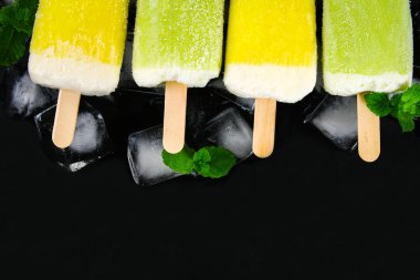 Sarı ve yeşil nane buz siyah bir tablo ile bir sopa dondurma meyve
