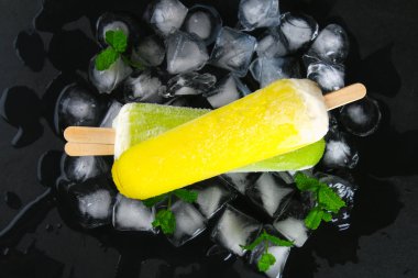 Sarı ve yeşil nane buz siyah bir tablo ile bir sopa dondurma meyve