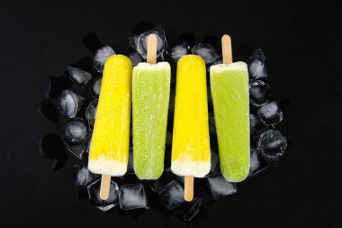 Sarı ve yeşil nane buz siyah bir tablo ile bir sopa dondurma meyve