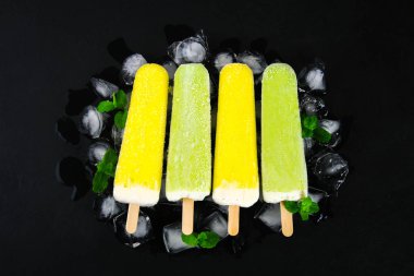 Sarı ve yeşil nane buz siyah bir tablo ile bir sopa dondurma meyve