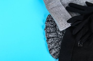 Kış ve sonbahar giyim, şapka, eşarp, eldiven pastel mavi bir arka plan üzerinde