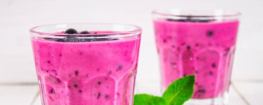 Beyaz ahşap bir masa üzerinde payet ile cam bardaklarda Siyah frenk üzümü smoothies