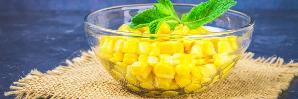 Canned corn in a glass plate on a gray concrete background