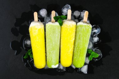 Sarı ve yeşil nane buz siyah bir tablo ile bir sopa dondurma meyve
