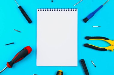 Ev, ev onarım, tadilatta, yenilenen konsepti. Mavi bir ızgara üzerinde onarım araçları kümesi: lay düz iki tornavida ve not defteri, üstten görünüm