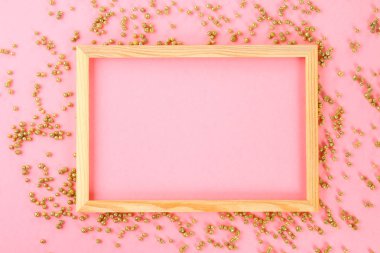 Parlak dekoratif yıldız ve topları çevrili pastel bir arka plan üzerinde ahşap bir boş çerçeve