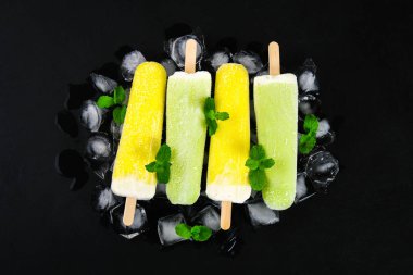 Sarı ve yeşil nane buz siyah bir tablo ile bir sopa dondurma meyve