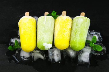 Sarı ve yeşil nane buz siyah bir tablo ile bir sopa dondurma meyve