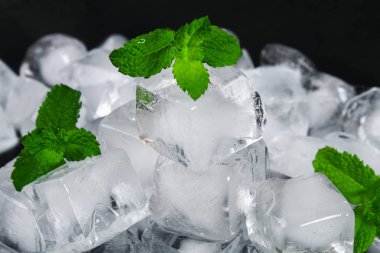 Küpleri buz su ile nane yaprakları üzerinde siyah bir arka plan
