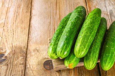 Eski bir ahşap masa üzerinde bir yaprak taze salatalık