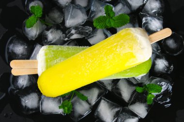 Sarı ve yeşil nane buz siyah bir tablo ile bir sopa dondurma meyve