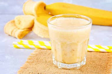 Bir kağıt tüp ve nane ile muz smoothie. Muz bütün ve gri arka plan üzerinde kesme