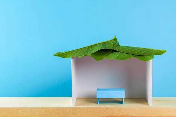 Mutlu Sukkot. Kağıttan yapılmış bir kulübe mavi bir arka plan üzerinde yapraklarla kaplı. Kopyalama alanı