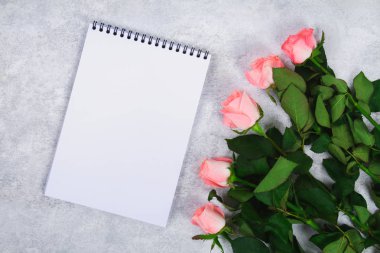 Pembe gül buketi ve kalem ile boş bir defter kalem hafif bir arka plan üzerinde