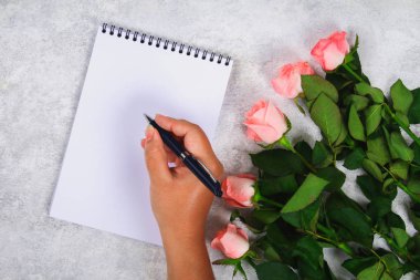 Pembe gül buketi ve kalem ile boş bir defter kalem hafif bir arka plan üzerinde