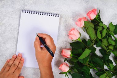 Pembe gül buketi ve kalem ile boş bir defter kalem hafif bir arka plan üzerinde