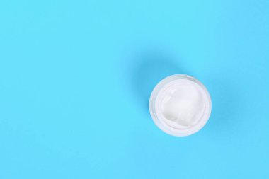 Krem üzerinde mavi pastel renkli plastik kavanoz açtı. Üstten görünüm. Kopya alanı