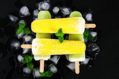 Sarı ve yeşil nane buz siyah bir tablo ile bir sopa dondurma meyve