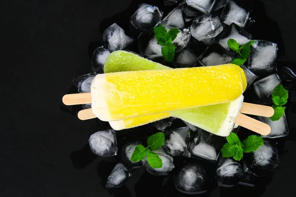 Желтое Зеленое Фруктовое Мороженое Палочке Мятой Льду Черном Столе — стоковое фото