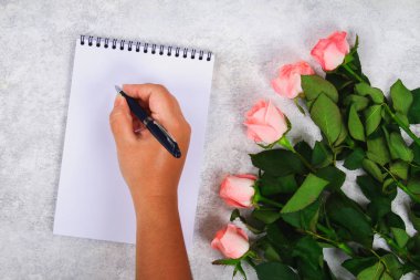 Pembe gül buketi ve kalem ile boş bir defter kalem hafif bir arka plan üzerinde