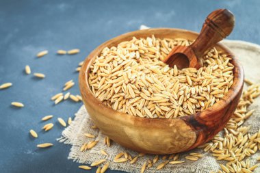 Ham ahşap kase ve gri bir tablo üzerinde kepçe Yulaf tanesi