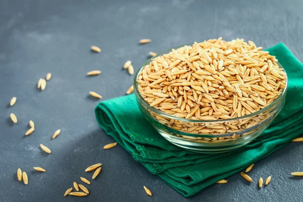 Gri bir tablo üzerinde bir cam kapta yulaf çiğ tanesi