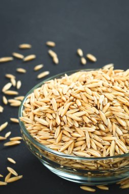 Gri bir tablo üzerinde bir cam kapta yulaf çiğ tanesi