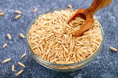 Gri bir tablo üzerinde bir cam kapta yulaf çiğ tanesi