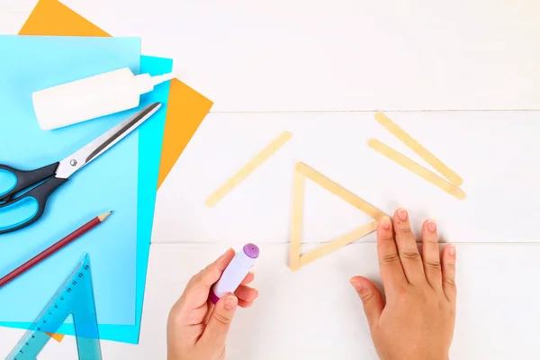 DIY. Davut'un Yıldızı dondurma dan elleriyle Beyaz ahşap bir masa üzerinde sopa