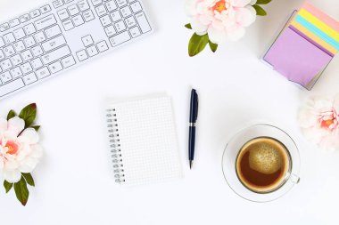 Boş bir beyaz Not defteri bir kupa kahve ve bir klavye yanında beyaz bir masaüstü. Üstten görünüm, düz düzen. Kopyalama alanı