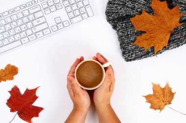 Hatmi bir boş blok ve klavye yanında beyaz bir masaüstünde elinde kahveyle, sonbahar yaprakları. Sonbahar ruh. Üstten görünüm, düz düzen. Kopyalama alanı