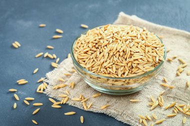 Gri bir tablo üzerinde bir cam kapta yulaf çiğ tanesi