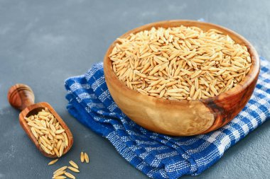 Ham ahşap kase ve gri bir tablo üzerinde kepçe Yulaf tanesi