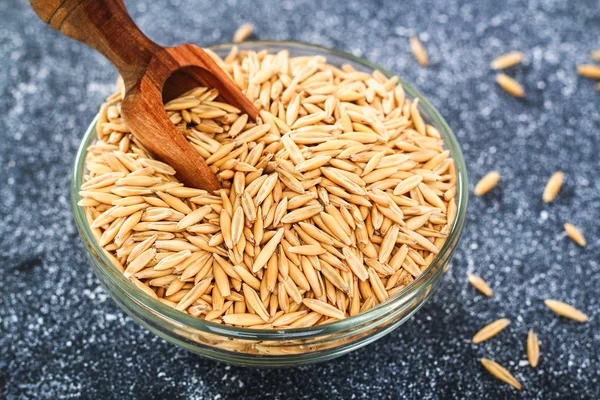 Gri bir tablo üzerinde bir cam kapta yulaf çiğ tanesi