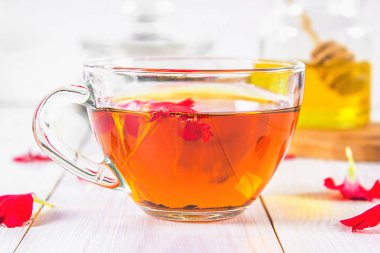 Bir fincan çay, bal ve bir kavanoz siyah bir bitki çiçek çayı ile bir banka beyaz ahşap bir masa üzerinde arka planda