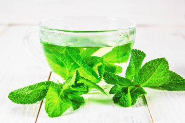 Beyaz ahşap bir masa üzerinde bir fincan nane çayı