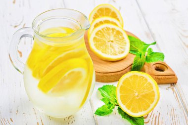 Bir sürahi soğuk limonata limon tarafından çevrili beyaz ahşap zemin üzerinde ile