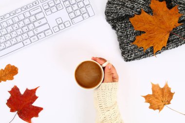 Hatmi bir boş blok ve klavye yanında beyaz bir masaüstünde elinde kahveyle, sonbahar yaprakları. Sonbahar ruh. Üstten görünüm, düz düzen. Kopyalama alanı