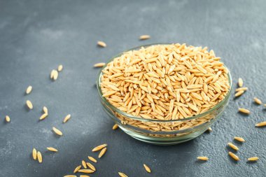 Gri bir tablo üzerinde bir cam kapta yulaf çiğ tanesi