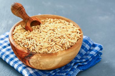 Ham ahşap kase ve gri bir tablo üzerinde kepçe Yulaf tanesi