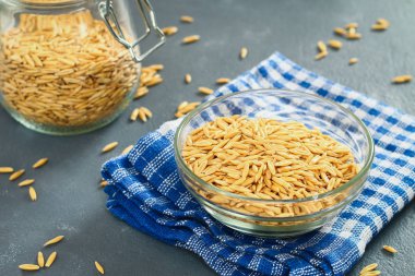 Gri bir tablo üzerinde bir cam kapta yulaf çiğ tanesi