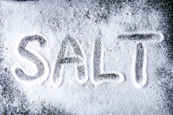 Ordet Salt Skriven Små Kristaller Salt Utspridda Ett Svart Bord — Stockfoto