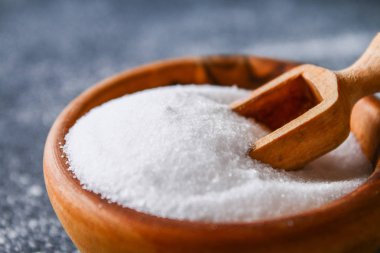 Bir koyu gri masada ahşap bir kasede sığ tuz kristalleri