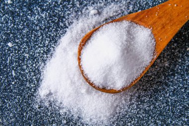 Bir kaşık kaşık bir koyu gri tabloda sığ tuz kristalleri