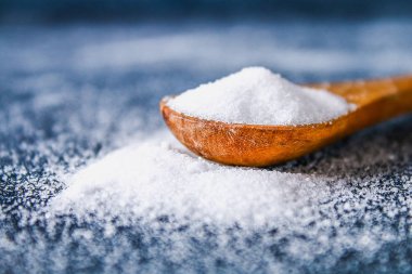 Bir kaşık kaşık bir koyu gri tabloda sığ tuz kristalleri