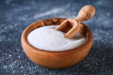 Bir koyu gri masada ahşap bir kasede sığ tuz kristalleri. Reklam tuz için arka plan. Tablo tuzlu. Tuzlanmış gıda