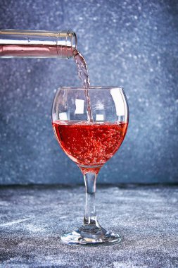 Cam şarap. Bir dere şarap şişe boyun dökülen. Gri bir arka plan üzerinde şarap
