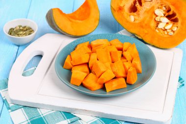 Kabak, balkabağı çorbası veya patates püresi yemek pişirmek için parçalar halinde dilimlenmiş. Mavi ahşap bir masa üzerinde kabak