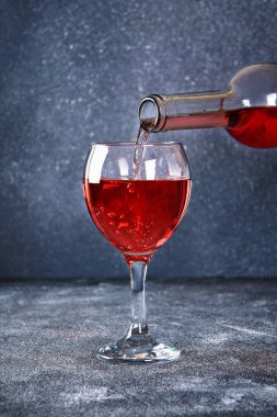 Cam şarap. Bir dere şarap şişe boyun dökülen. Gri bir arka plan üzerinde şarap